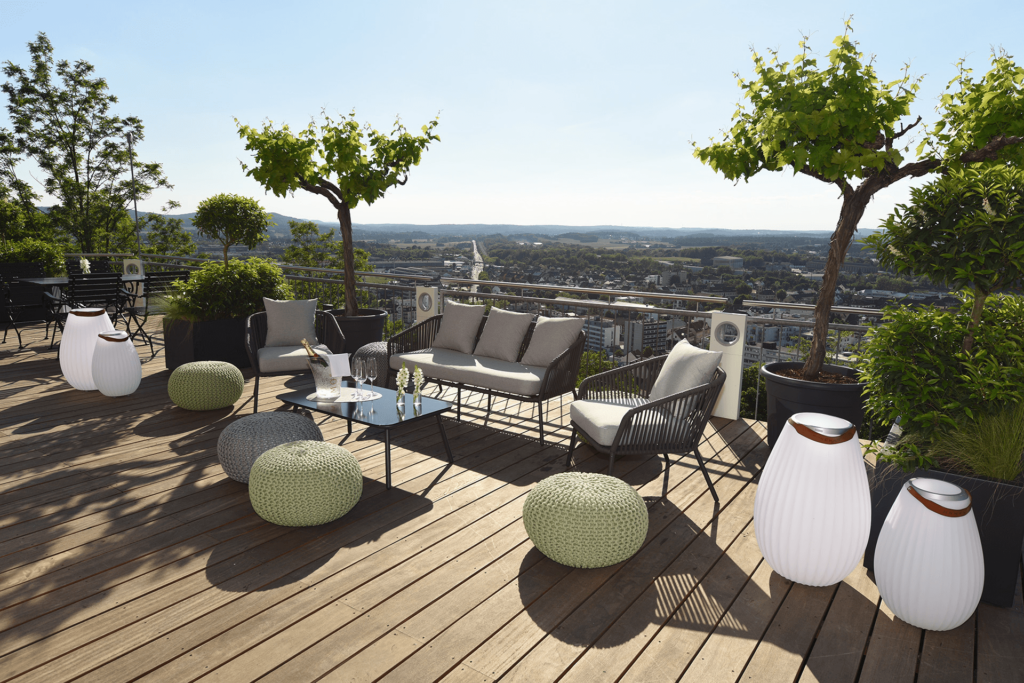 Sitzlounge auf der Panoramaterrasse mit Sitzhockern und Outdoorcouch mit Blick auf die Stadt bei blauem Himmel