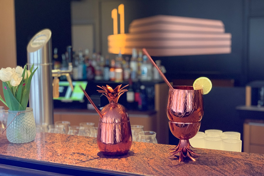 An der Theke der Bar stehen zwei Kupferfarbene Gläser mit Strohhalmen und Dekoration am Glasrand