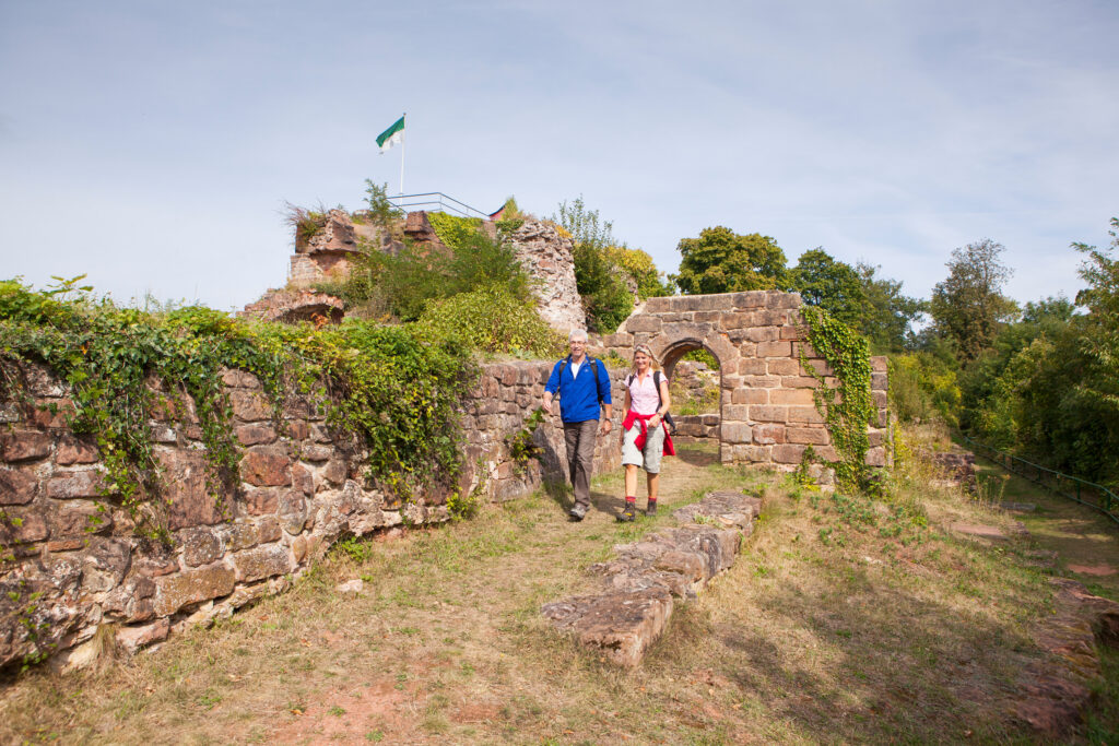 Mann und Frau wandern über die Ruine des Schlossberg bei sonnigem Wetter
