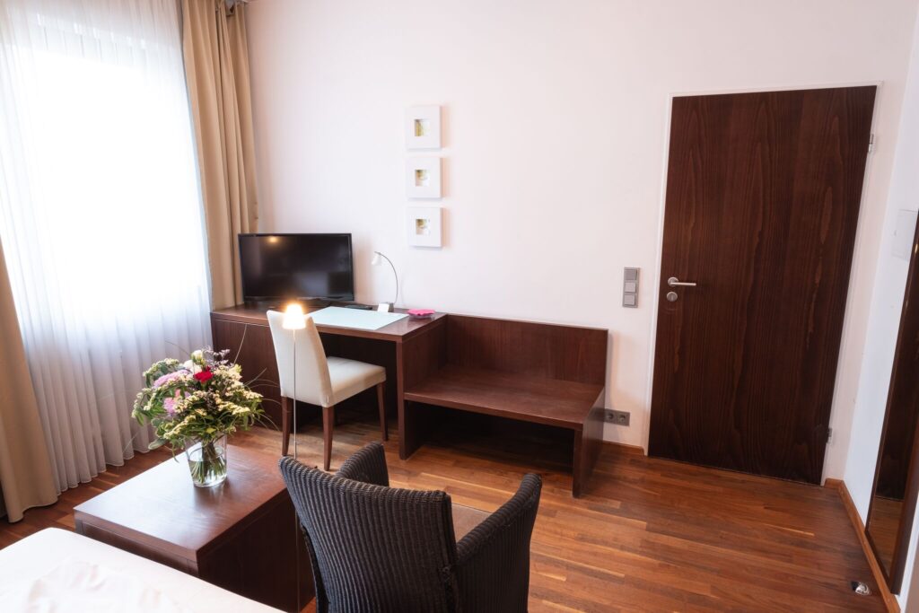 Studio Apartment des Schlossberg Hotels mit min. 23qm sicht vom Bett aus auf Arbeitsbereich mit Bank und TV